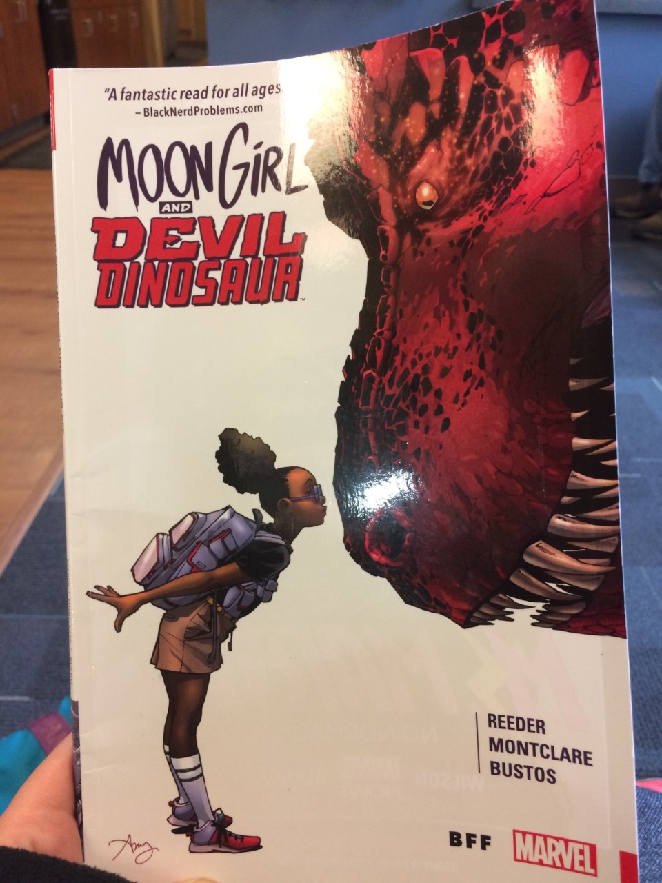 [Image is a cover of a graphic novel that I'm holding. The graphic novel is Moon Girl and Devil Dinosaur. It shows a young girl kissing a red dinosaur]