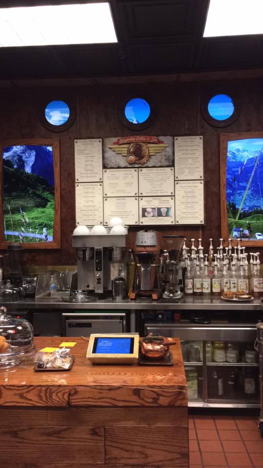 [Image shows an order counter. The order counter looks like a back of a pirate ship. There are two big screens and in between the screens are the menu. There are multiple coffee machines and syrups for coffee]