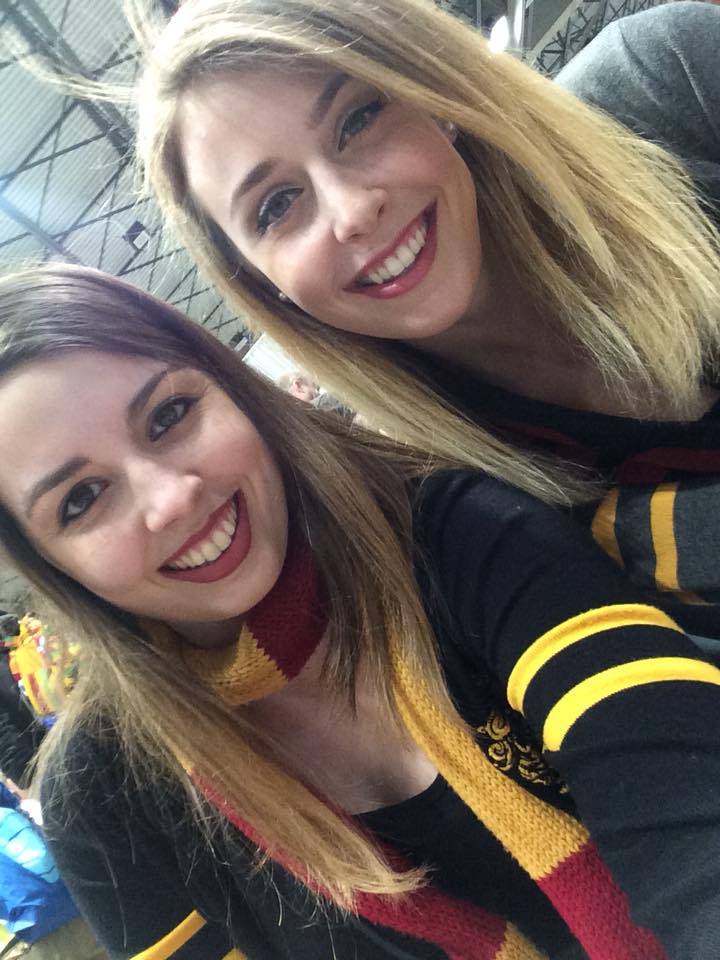 [Image is a selfie of two women. One is wearing a scarf and red lipstick, the other one is blonde and wearing a Hogwarts sweater]