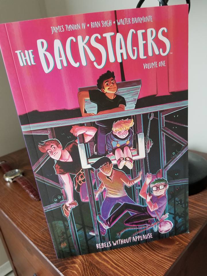 [Image is a graphic novel cover. The cover shows five characters on a stage set. The title says "The Backstagers Volume One"]