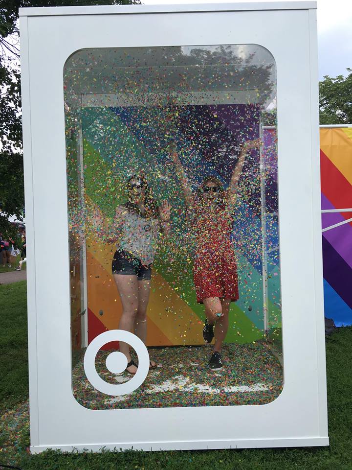 [Image is a picture of a white booth. In the booth, there are two people with confetti covering their bodies]