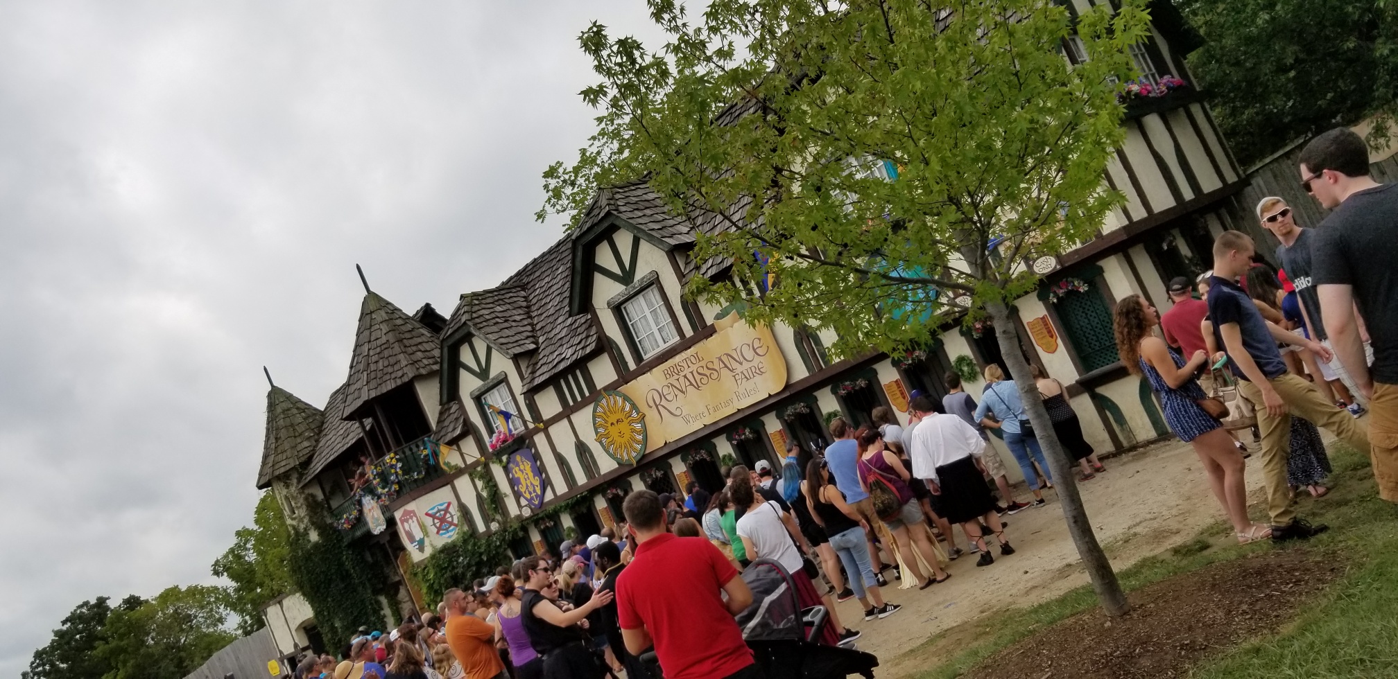 [Image is the entrance of the Bristol Renaissance Faire" A sign is shown on a few older looking buildings]