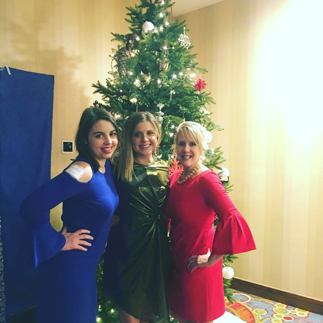 [Image is of three women smiling. They are all dressed formally]