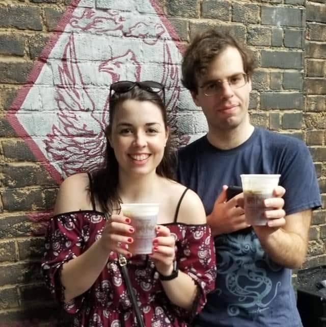 Image is a photo of me and my brother. We are smiling and holding our butterbeers to the camera. 