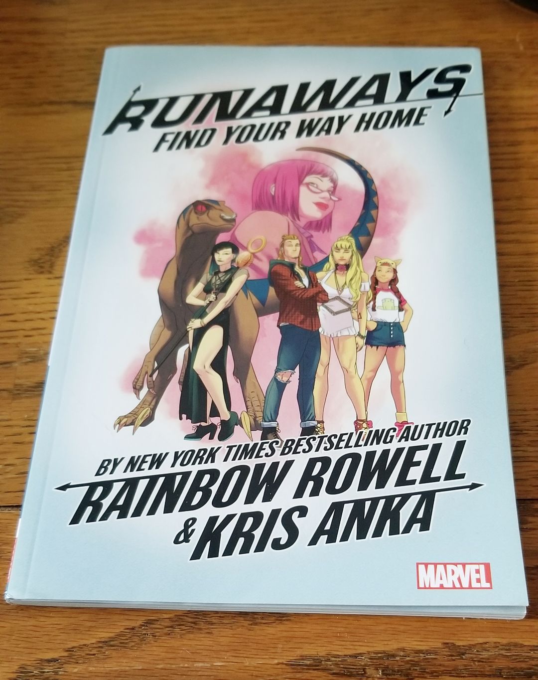 Image is a photo for the graphic novel Runaways Find Your Way Home by Rainbow Rowell. It shows a dinosaur and five individuals standing front and center. 