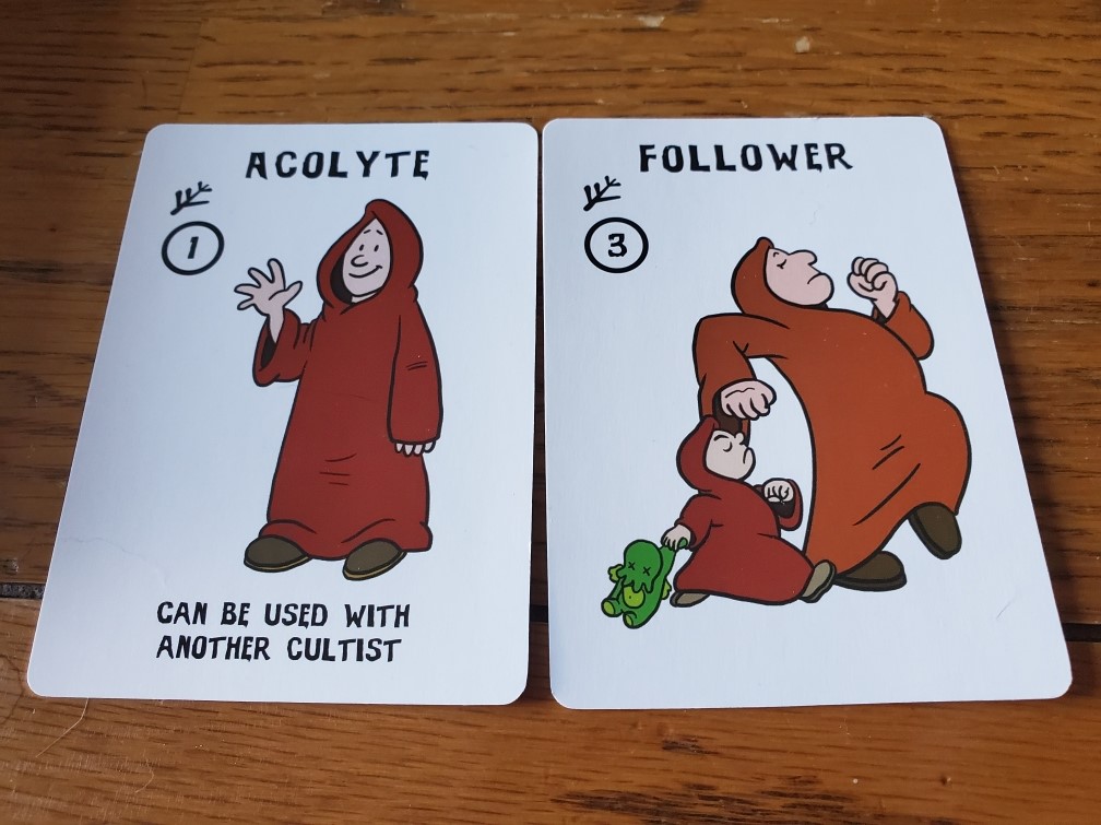 Image is of two cards side by side. On the left it says Acolyte with a person wearing an oversized brown cloak. They are waving. The card on the right is a Follower card. It shows two people walking to the right on the card. 