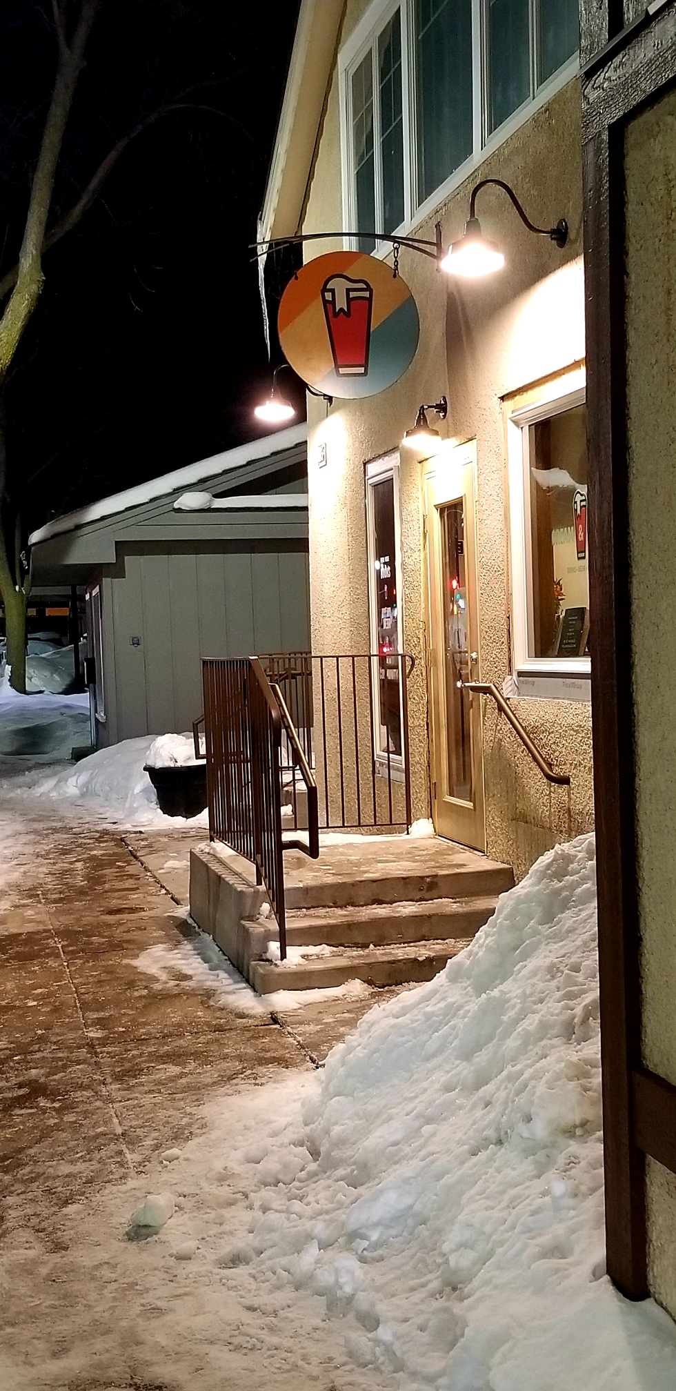 Image is a photo of Cream & Amber bookstore. There's piles of snow everywhere. There's a set of three stairs leading to Cream and Amber's door. 