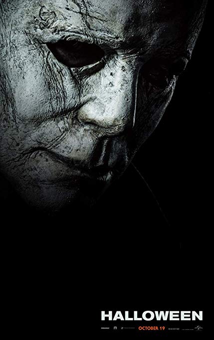 Image is a promotional poster for the movie, Halloween. It shows a close up, black and white, gritty photo of Michael Myer's mask. 