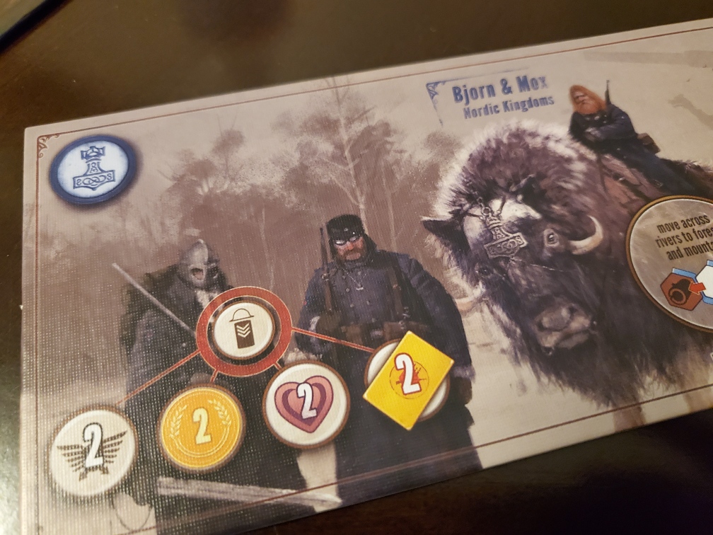 Image shows a game board piece from the board game, Scythe. This is the Nordic game piece. It shows three men dressed in Viking like clothing. One man is on top of a bison. 
