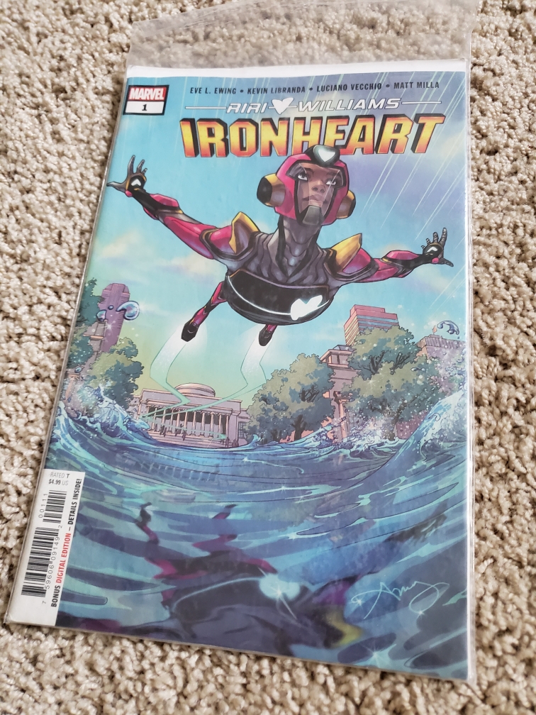 Image is of a single issue comic for Riri Williams Ironheart. It shows a girl in an Iron Man suit flying over the water. The water is pushed away from her. 