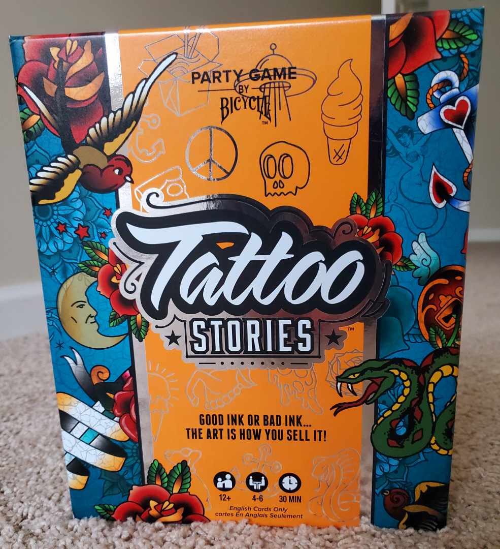 Image is a photo of a board game called Tattoo Stories. On the left and right columns, it shows various tattoo art. The board game says on the cover, "Good Ink or Bad Ink The Art is How You Sell It" 