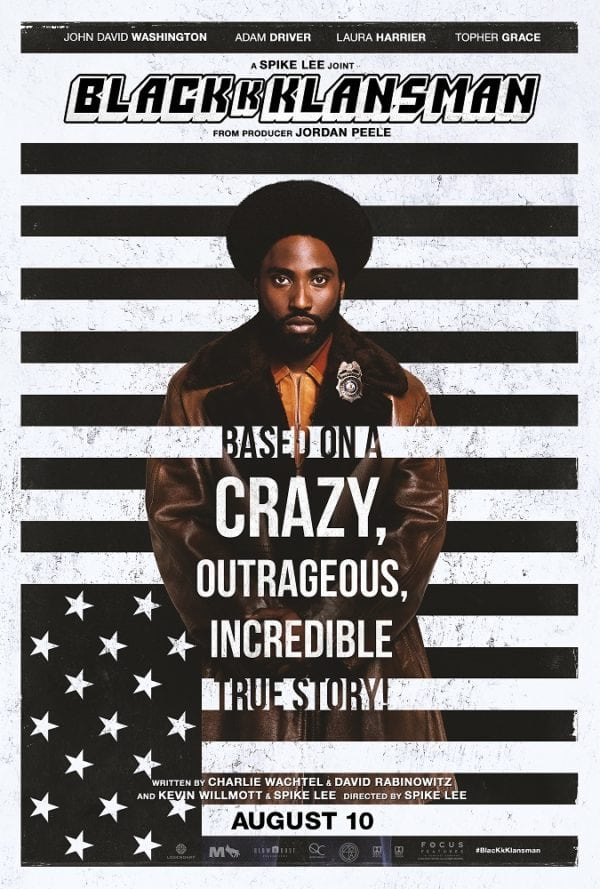 Image is a movie poster for BlackKkksman. It shows a man standing behind a vertical white and black horizontal pattern. It's the American Flag if the American flag were black and white.
