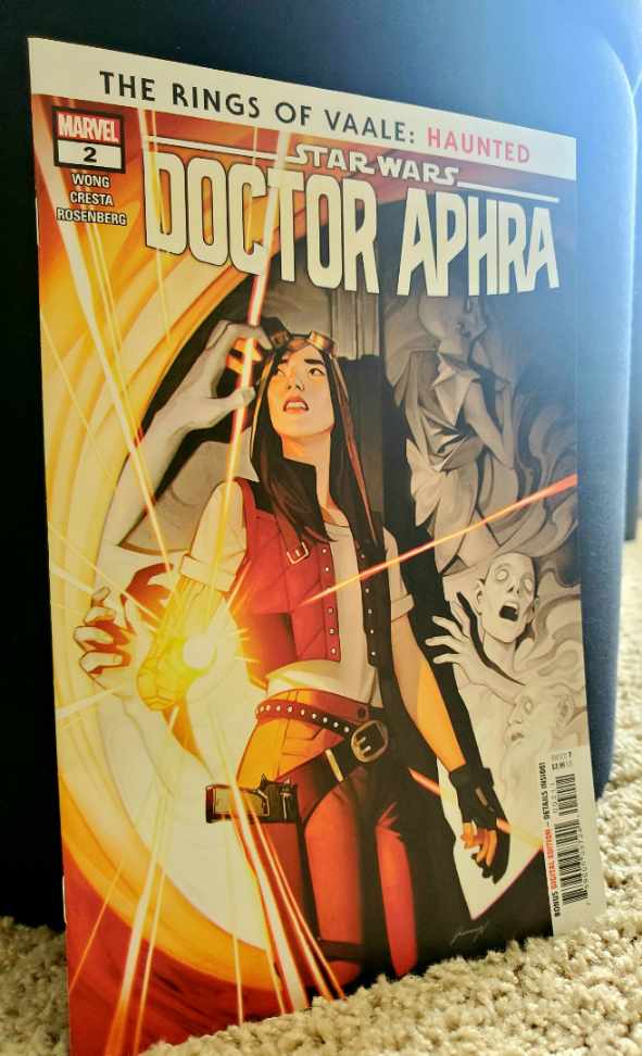 Image is a comic book cover for the comic, Doctor Aphra The rings of Vaale: Haunted. It shows a woman with goggles on her head. She's holding something that's giving off light. There are white bodies to her right that look ghostly in nature. 