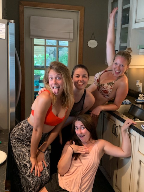 Image is a photo of four women smiling at the camera. 