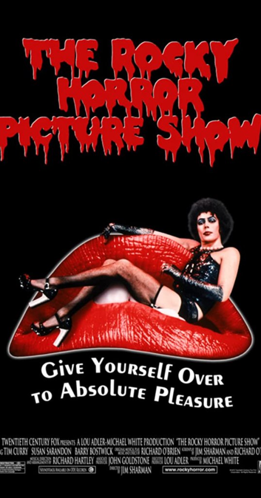 Image is a movie poster for Rocky Horror Picture Show. The font for Rocky Horror Picture Show is red and it appears as blood dripping down. It shows Dr. Frank-N-Furter sitting on red lips in black lingerie. It says below that "Give Yourself Over To Absolute Pleasure". 
