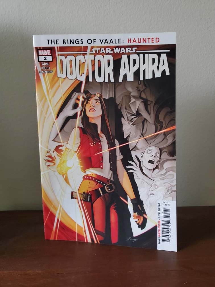 Image is a photo of Star Wars Doctor Aphra issue #2. It shows Aphra holding a flashlight. Behind her are these gray spirits of sorts staring at her. One is trying to grab her arm. 