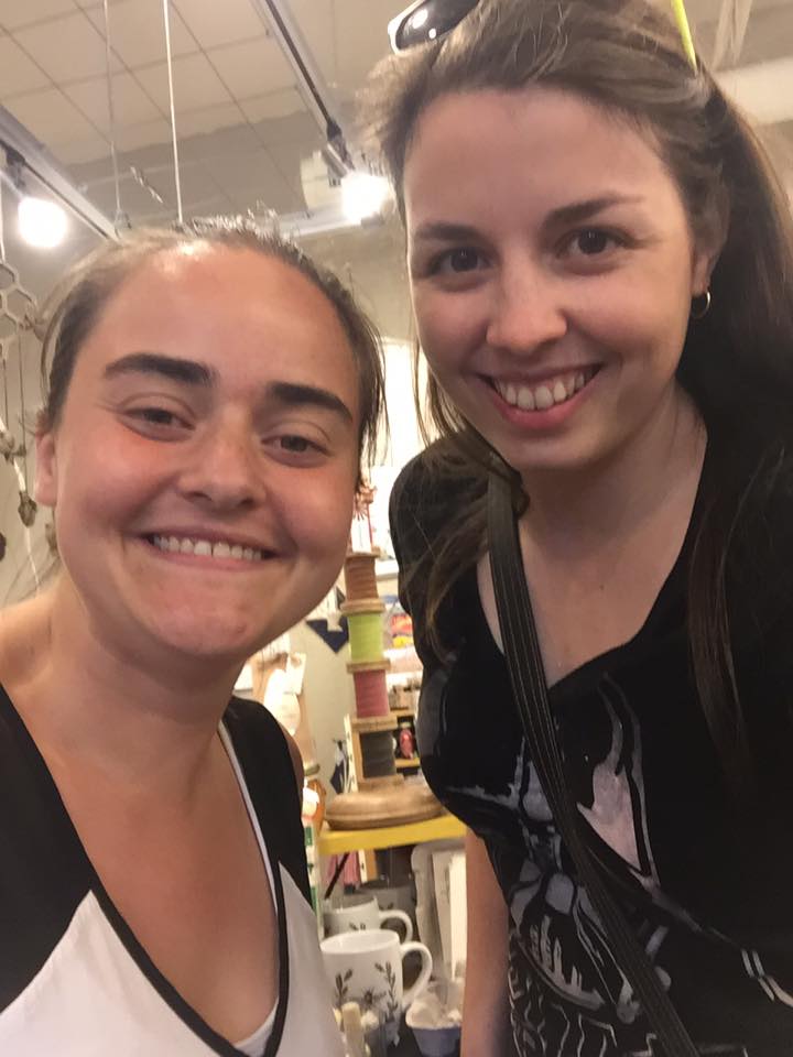 Image is a photo o fme and my friend. We are smiling at the camera. I'm wearing a Darth Vader shirt with sunglasses on my head. 