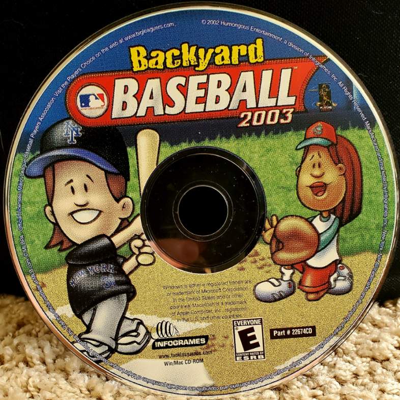 Image is a photo of Backyard Baseball 2003 Computer CD disc. It shows two cartoon or animated people. The first is a man from New York swinging a bat. Behind him, a girl is holding her mitt attempting to catch the ball.