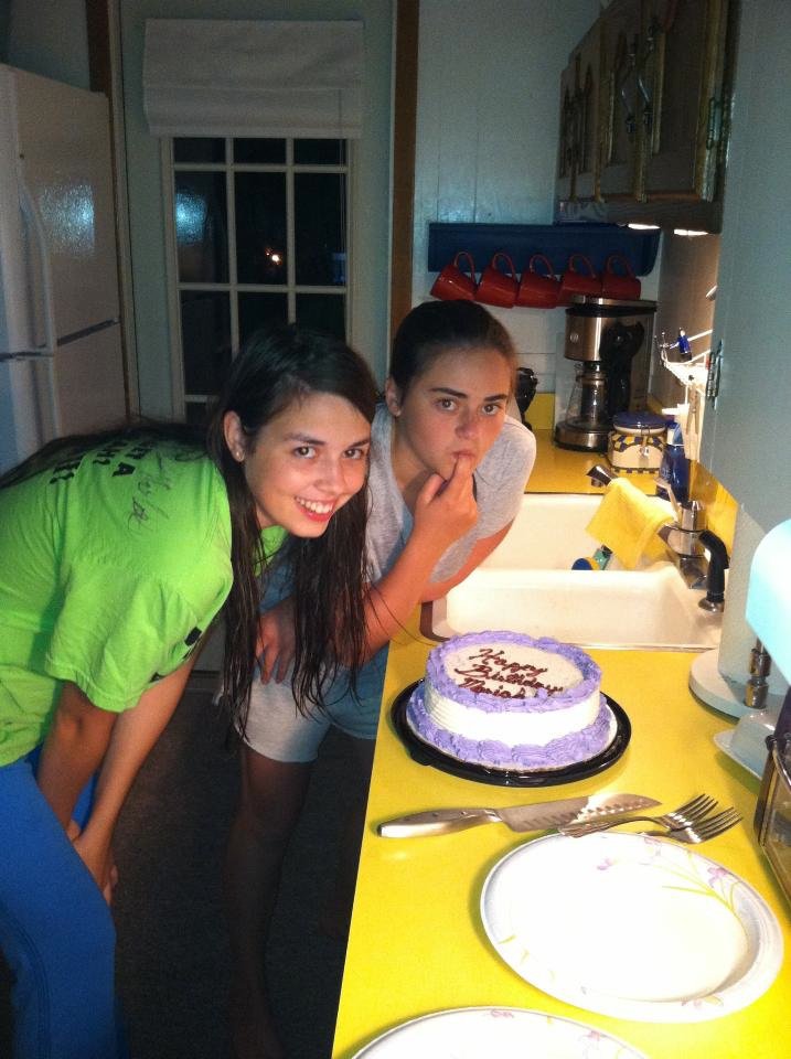 Image is a photo of me and my friend leaning over a birthday cake. 