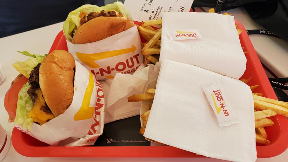 Image is a photo of a burger tray from In-N-Out. There are two burgers and two fries. 