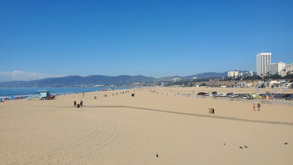 Image is a photo of a beach with the ocean and the mountains in the background. 