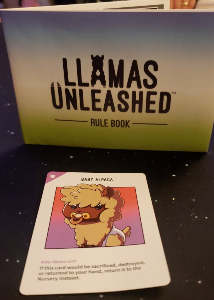 [Image features a game called Llamas Unleashed. Towards the bottom of the game, there's a card displayed. It says "Baby Alpaca featuring a baby cartoon Alpaca with a pacifier.]