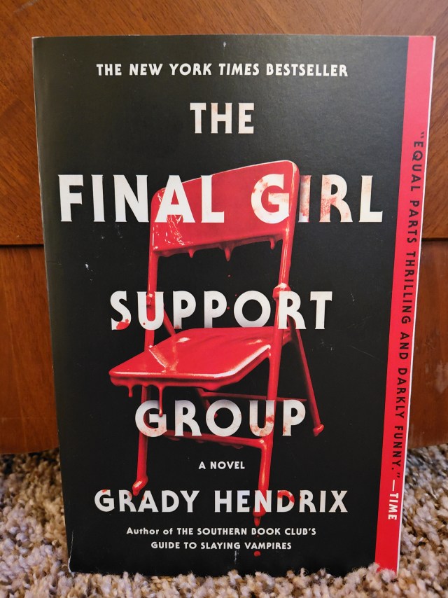 Image is a photo for a book cover for The Final Girl Support Group. The book cover is black, but zoomed in is a red plastic chair. 