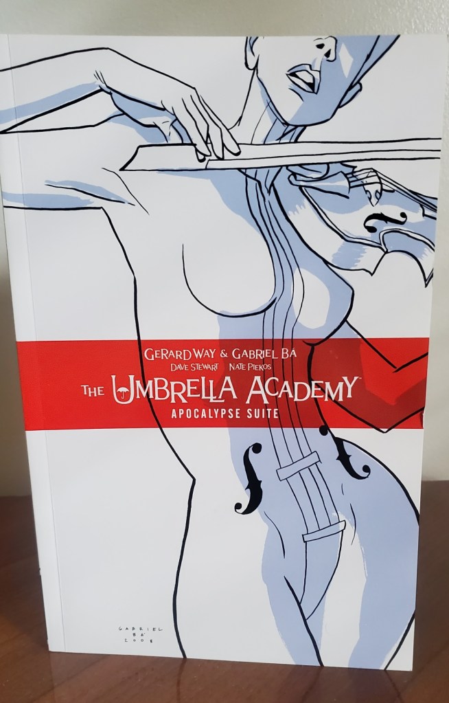 [Image is a graphic novel cover. It shows a woman in white with black outlining playing a violin. In the middle it says "The Umbrella Academy Apocalpyse Suite" by Gerard Way & Gabriel Ba] 