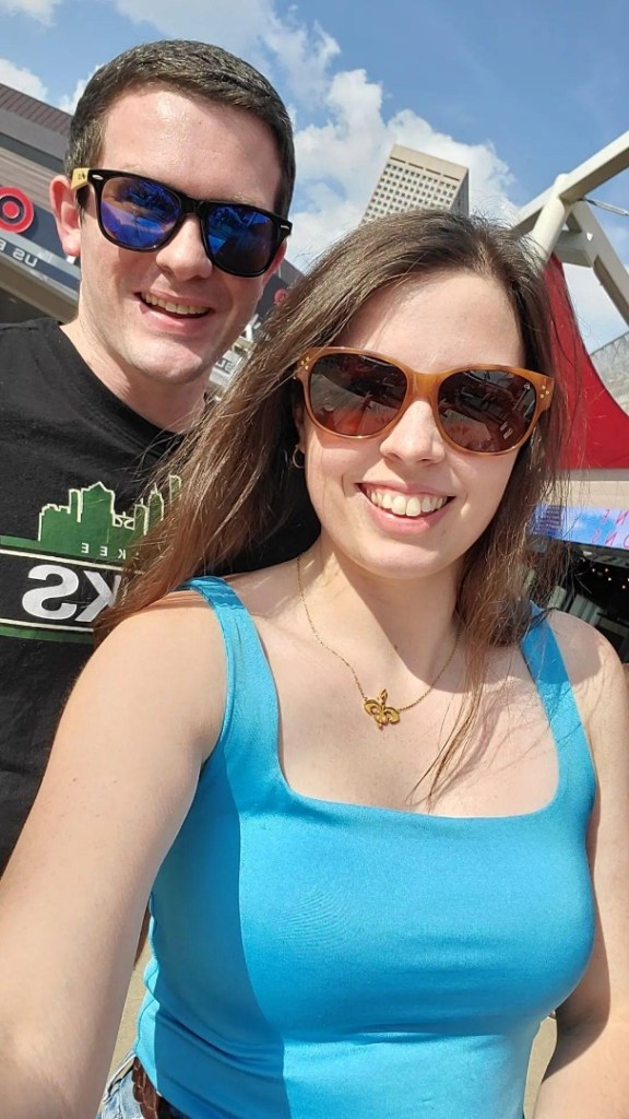 [Image is a selfie of a man and a woman. They are both smiling into the camera. They are wearing sunglasses because the sun is really bright]