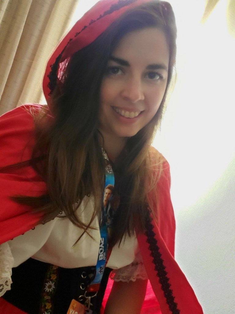 [Image is a selfie of a woman wearing a red cloak. She's similing at the camera]