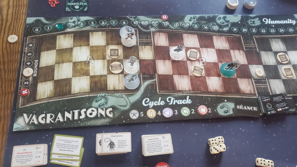 Image is a bird's eye view of a board from the board game Vagrant Song. There is a Humanity track at the top with numbered hearts from 0 - 25. In the middle of the board are different panels or train carts that serve as spaces for the characters to move. At the bottom it says "Vagrant Song" with a musical note in the middle of the O. 