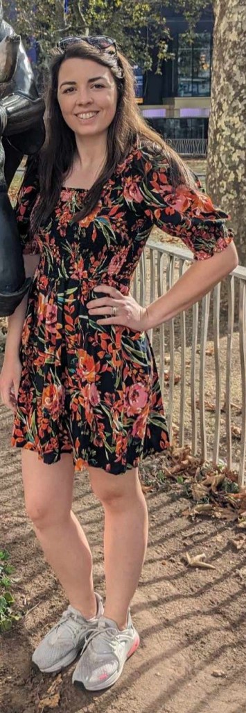 Image is a photo of me smiling at the camera. I'm wearing a black and floral dress.