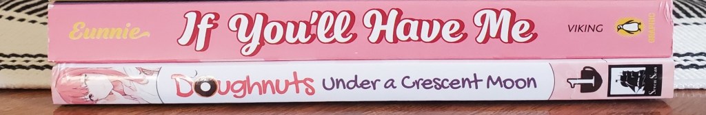 Image is two books stacked on top of each other. Their spines are both pink. The first is "If You'll Have Me" by Eunnie and the bottom book is "Doughnuts Under a Crescent Moon" by Shio Usui