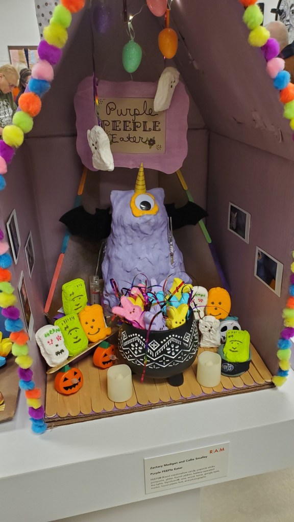 Image is a huge purple monster with one eye. In the cauldron are peeps. There's a skeleton peep and a few green Frankenstein peeps.