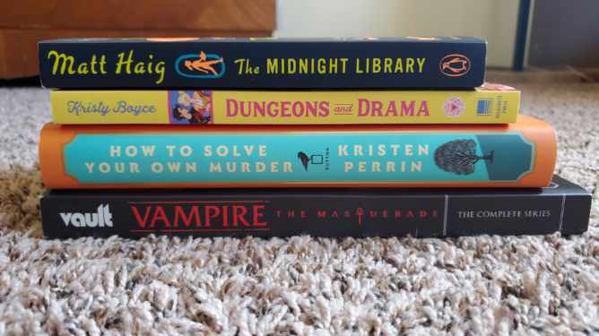 Image is a stack of three books and one graphic novel. From top to bottom it's The Midnight Library by Matt Haig, Dungeons and Drama by Kristy Boyce, How To Solve Your Own Murder by Kristen Perrin and Vampire the Masquerade The Complete Series. 
