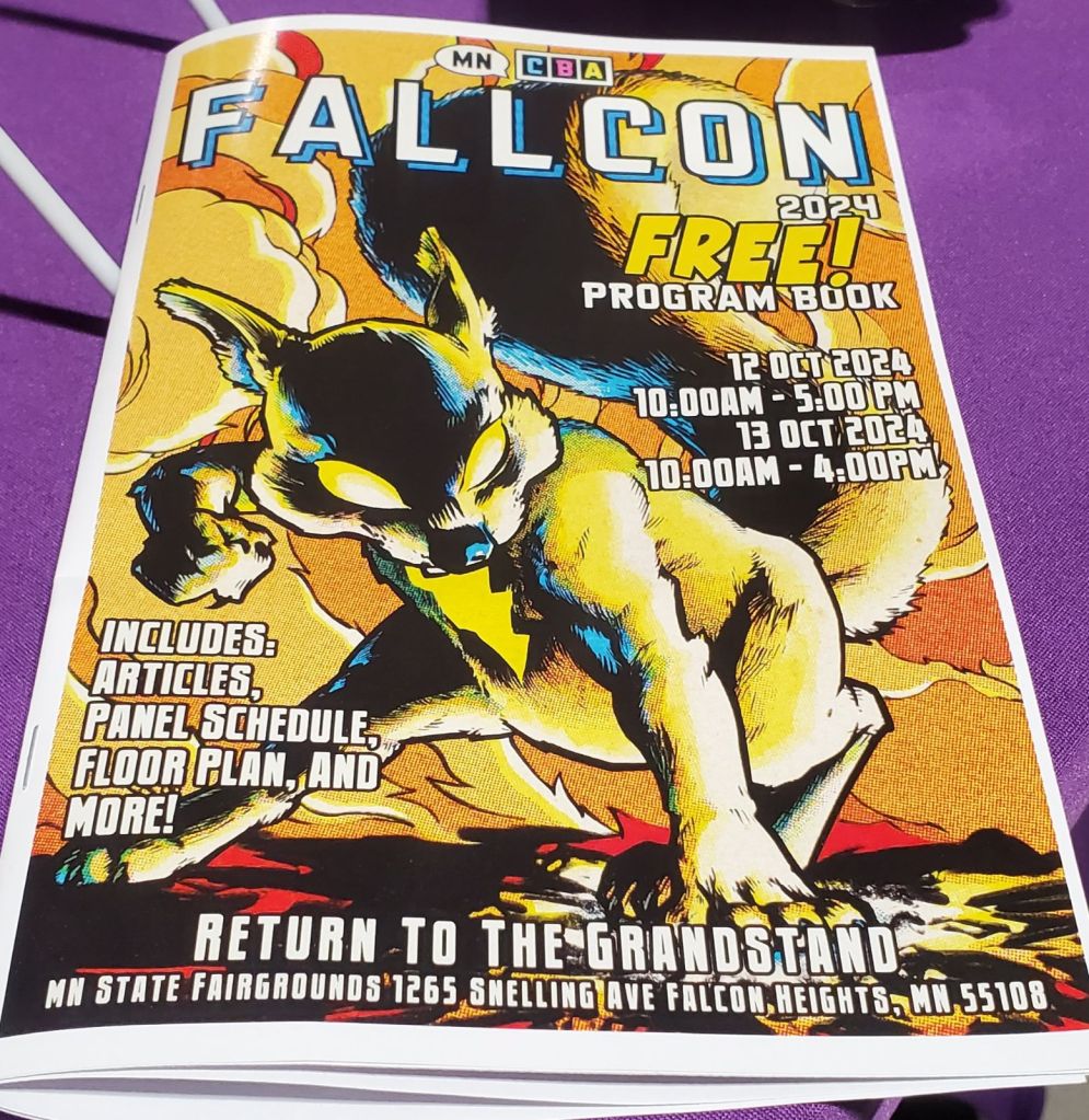 Image is a photo of the FallCon brochere. It has a glowing squirrel lit up by black and yellow. 