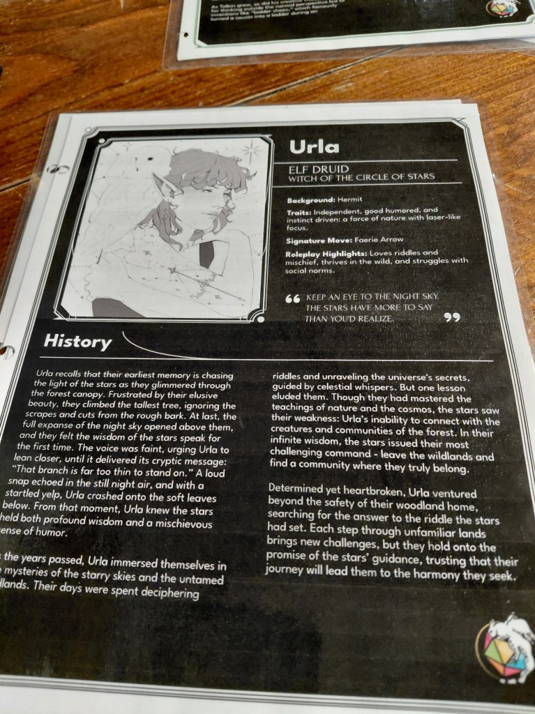 Image is a laminated character sheet in black and white. On the top right, it says Urla Elf Druid Witch of the Circle of Stars. Below that, it lists Background, Traits, Signature Move, and Roleplay highlights. To the left, it shows art of a feminine half-elf with elf ears. There's a white, snowy owl on her shoulder. There's a section titled HIstory which lists paragraphs of what Urla has been up to prior to the one-shot. 
