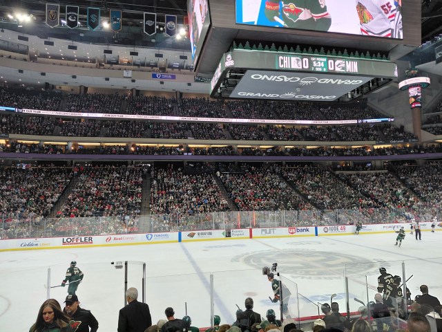Image is a photo of an ice hockey arena, specifically the Minnesota Wild's arena. It shows a few players skating around.